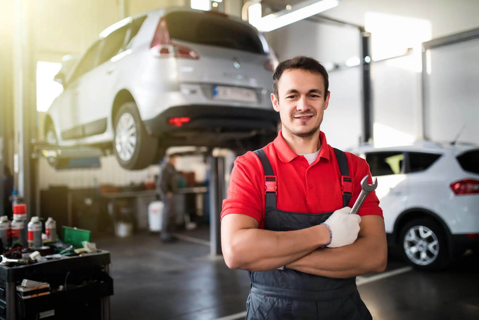 A mechanic in his own repair shop, arms crossed and smiling